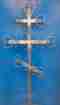 Grabkreuz aus Metall vor blauem Hintergrund